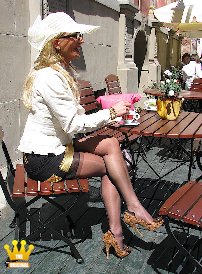 Lady Ewa : Lady Ewa sitzt in einem eleganten beige-schwarzen Kostüm mit Hut im Cafe, damit sich ihre Füße etwas vom Laufen in den engen, 14cm hohen Pumps erholen. Ihr kurzer schwarzer Rock ist soweit hochgerutscht, dass die Strumpfansätze ihrer hauchdünnen schwarzen Nahtnylons zu sehen sind. Dann geht es auch schon weiter, quer über den Marktplatz, wo sie regelrecht begafft wird.