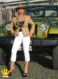 Lady Barbara : In a cowboy outfit with a tight white leggings and 18cm high heeled plateau mules I posed today in front of my green Jeep. On request of a present Member, Im also presenting my big boobs with the stiff nipples which I pull out of the shirt, so that men in the old building have something to watch.