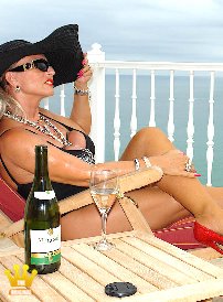 Lady Barbara : In a black bathing suit and red 16 cm high crocodile pumps I am posing with a lot of jewelry and a big summer hat on the terrace of my villa in Spain at 30 degrees in the shade. I enjoy an ice-cold, delicious white wine - before breakfast. Do I have bare legs, or do I wear sheer skin-colored tights? Take a close look.
