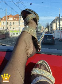 Lady Katinka : Bei einer Fahrt durch Bonn zeigt Katinka heute ihre Füße in hauchdünnen mokkafarbenen Nylons und 15cm hohen Strass-Pantoletten mit Plateau. Sie hält ihre Füße bei der Fahrt mit und ohne Schuhe auf dem Armaturenbrett und fotografiert sich selbst.